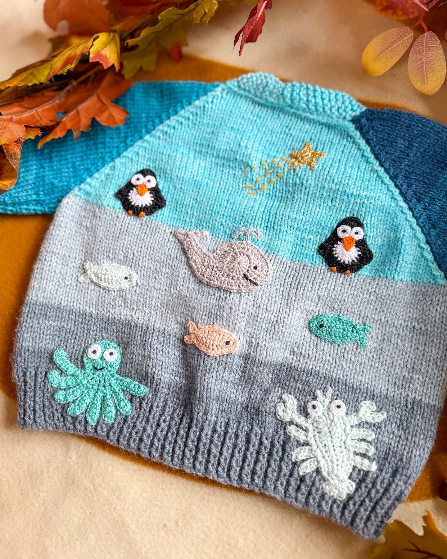 Arctic animals baby cardigan featuring playful penguin and sea creature embroidery on a knitted fabric