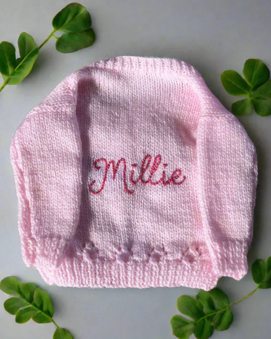 Pink hand-knitted baby cardigan with the name Millie embroidered and design a unique cardigan on our Knit Builder