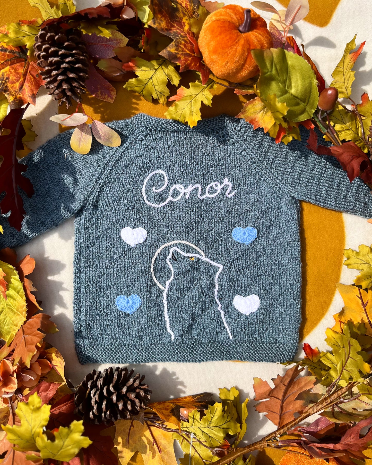 Handknit teal baby cardigan embroidered Conor with wolf outline and hearts autumn setting unique boy wolf gift ideas