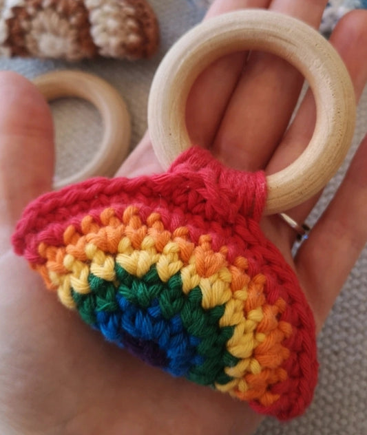 Little Flower Knits crochet baby teether with wooden ring and handmade rainbow crochet cover held in hand