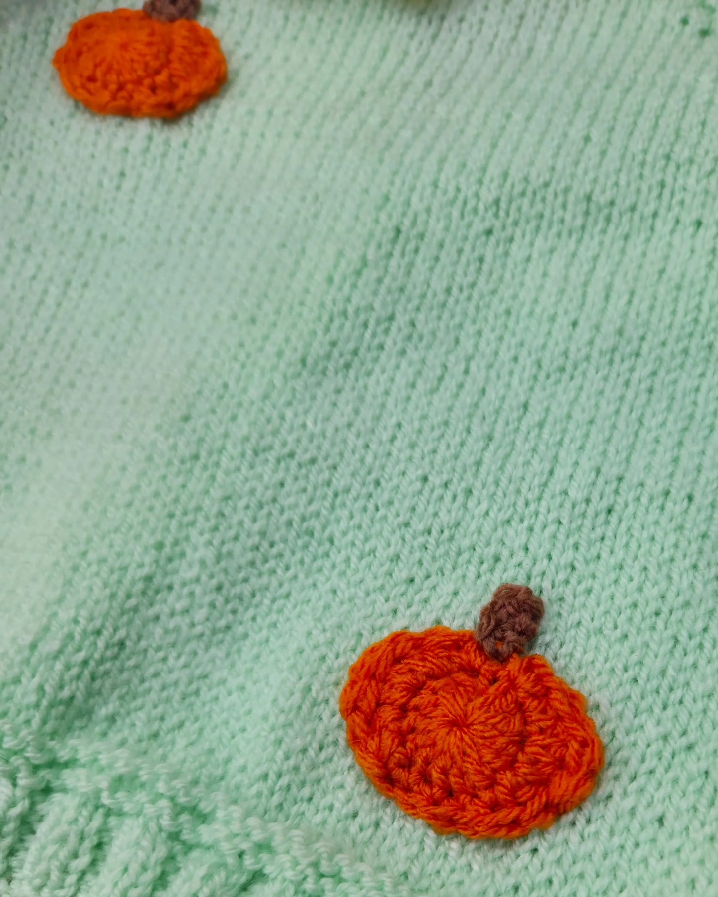 Mint green handknit fabric with orange crocheted pumpkin appliques on a soft sweater custom pumpkin outfit for toddlers