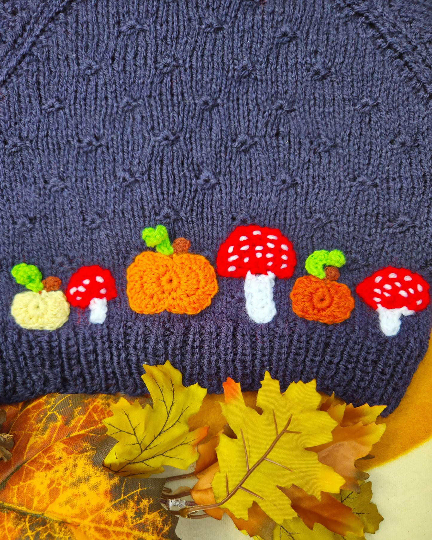 Little Flower Knits dark blue jumper hem with autumn appliques featuring hand-knitted pumpkin and toadstool costume motifs