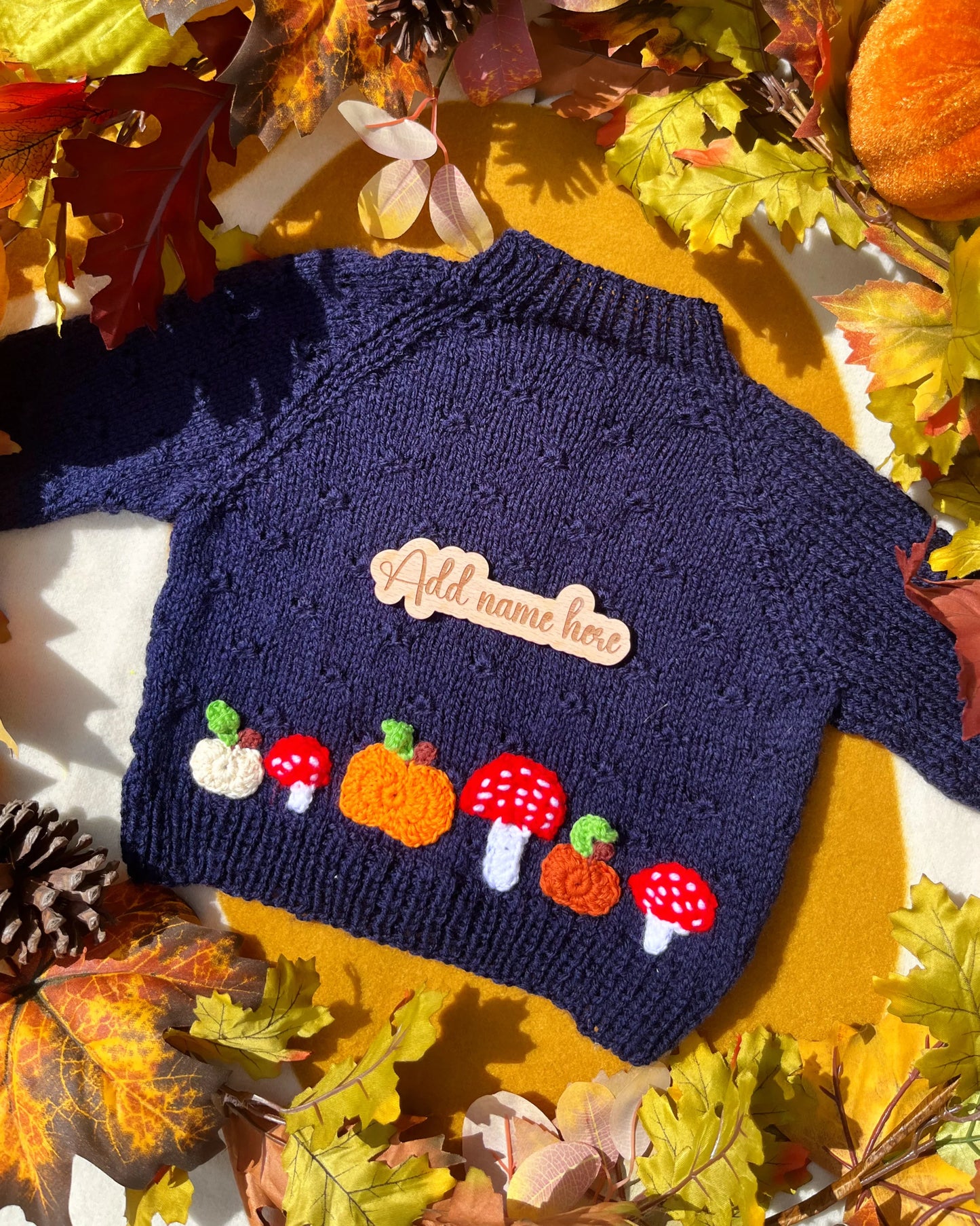 hand-knitted pumpkin and toadstool costume navy baby sweater with pumpkins toadstools and wooden name tag by Little Flower Knits