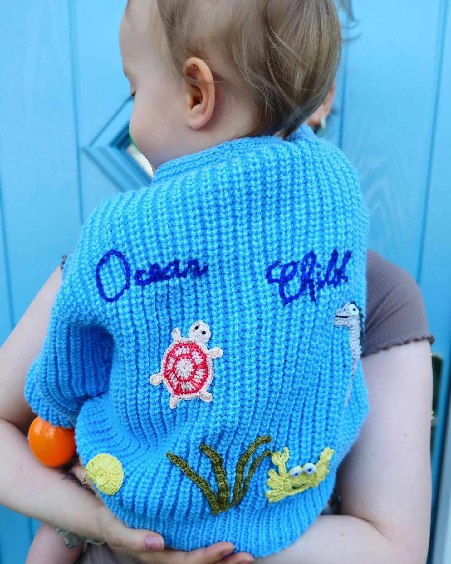 Handmade ocean theme baby knitwear UK blue sweater with turtle crab and seaweed on back