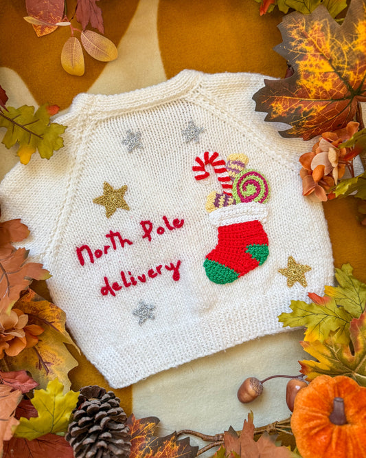Hand-knitted North Pole delivery cardigan 12-18 months featuring festive designs and vibrant colours
