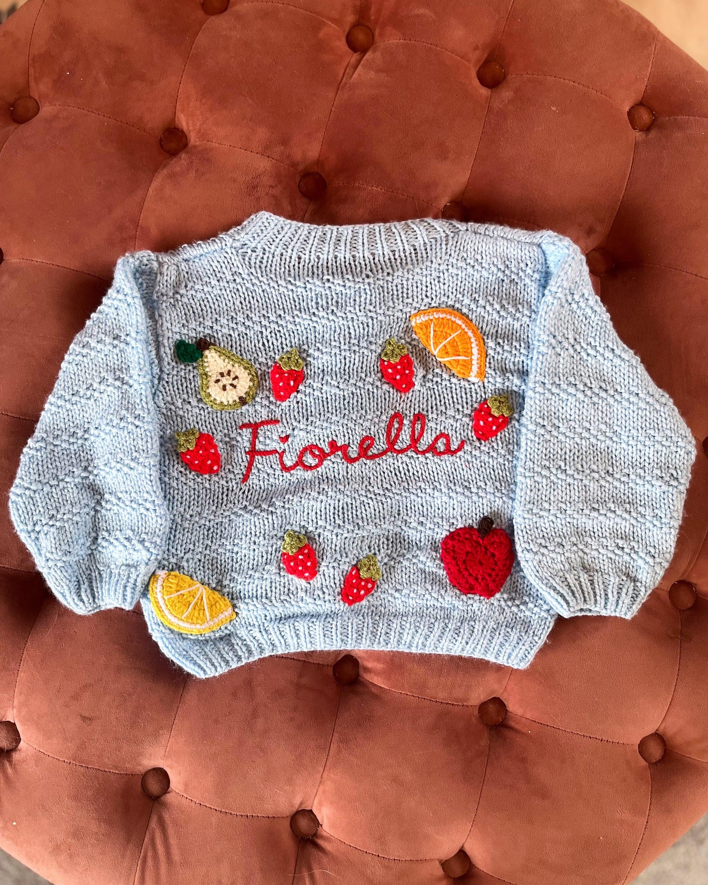 Light blue personalised baby cardigan UK with embroidered fruit and the name Fiorella on the back