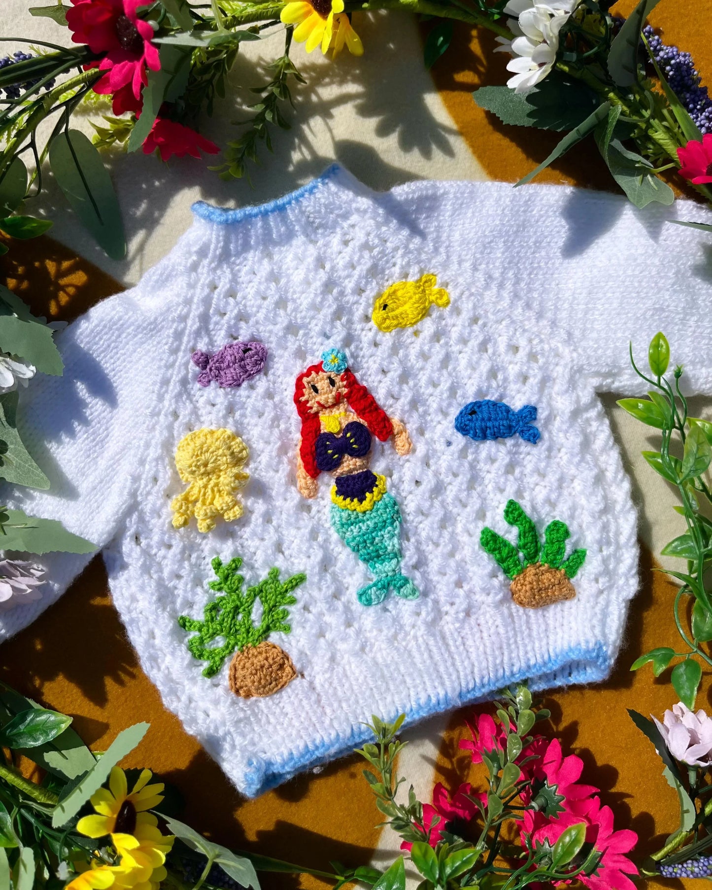 White personalised mermaid cardigan with colourful knitted mermaid and sea creatures design surrounded by flowers