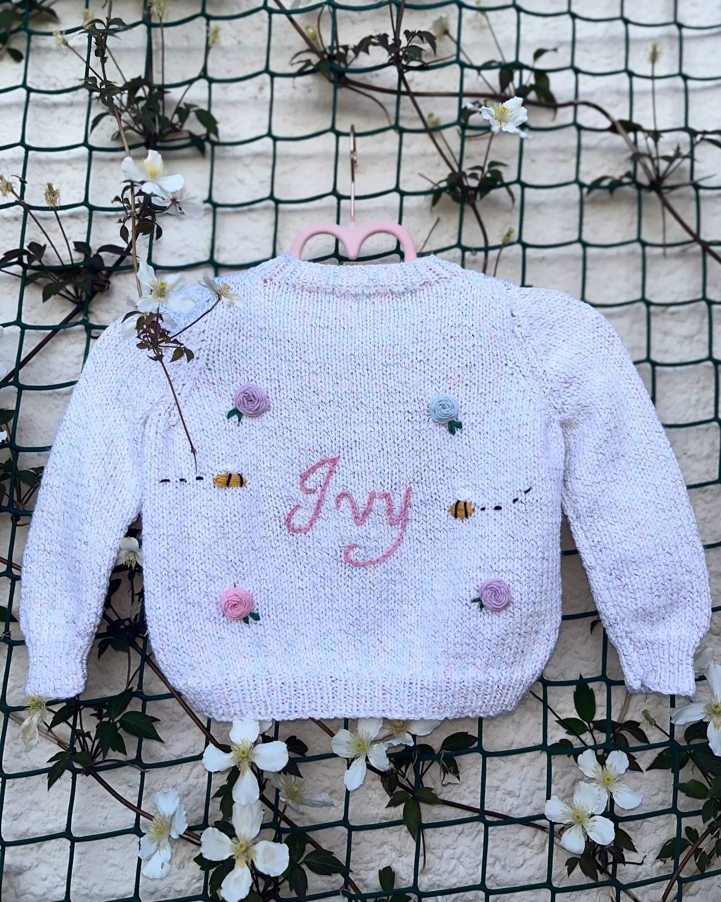 Handmade personalised rose and bee cardigan in soft pastel with embroidered name Ivy and floral embellishments