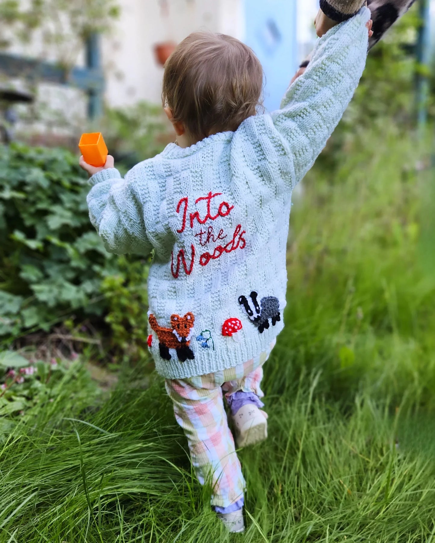 Child wearing a personalised woodland cardigan for children featuring embroidered woodland animals and text