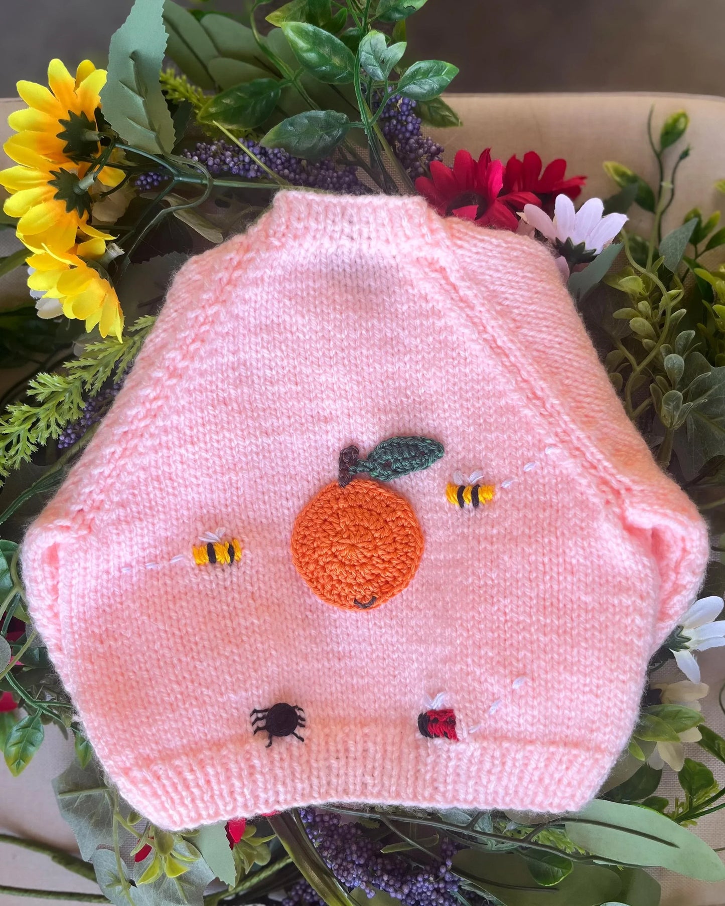 Unique baby shower gift knitted pink baby vest with embroidered orange, bees, spider, and ladybird details