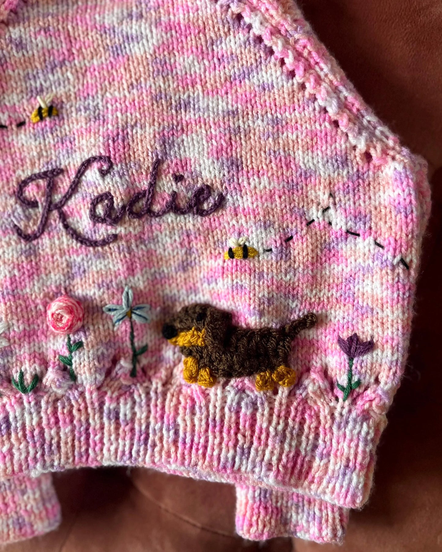 Close-up of a unique floral cardigan for girls by Little Flower Knits featuring embroidered flowers and a small dog