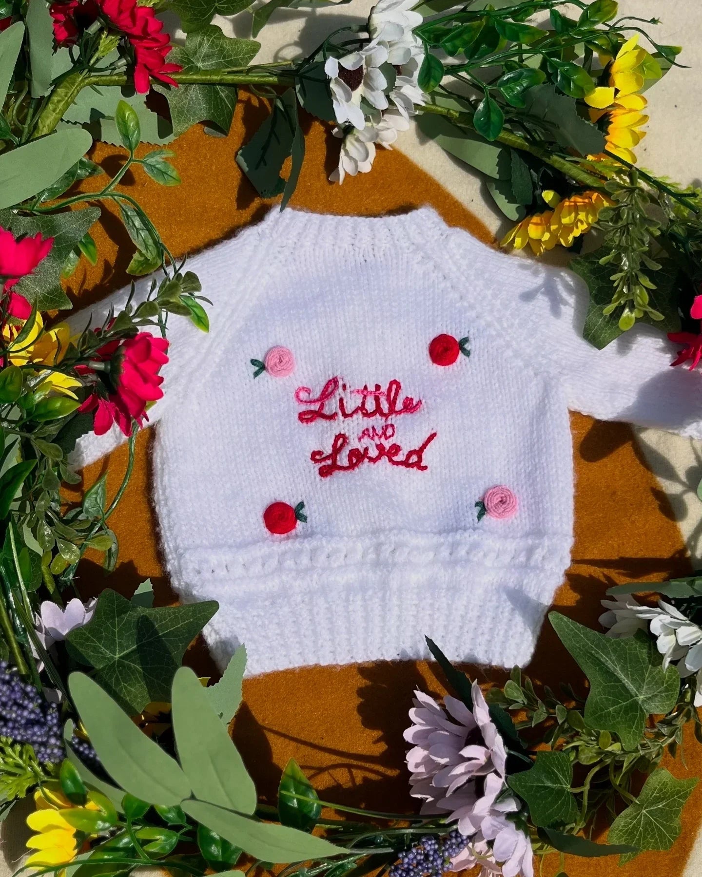 White baby jumper with Little Flower Knits unique personalised baby gift embroidery surrounded by colourful flowers