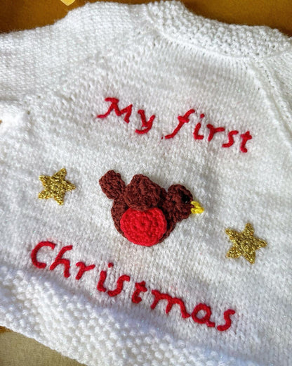 White baby's first Christmas cardigan with red text and a cute bird design on the back