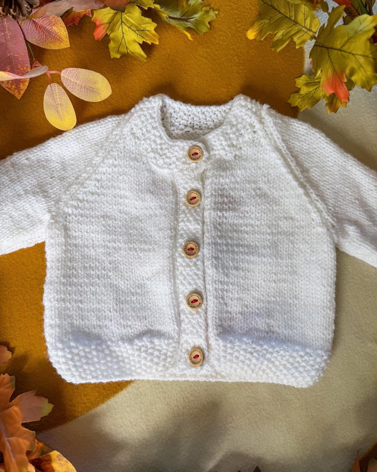 Soft white baby's first Christmas cardigan with wooden buttons, perfect for festive occasions