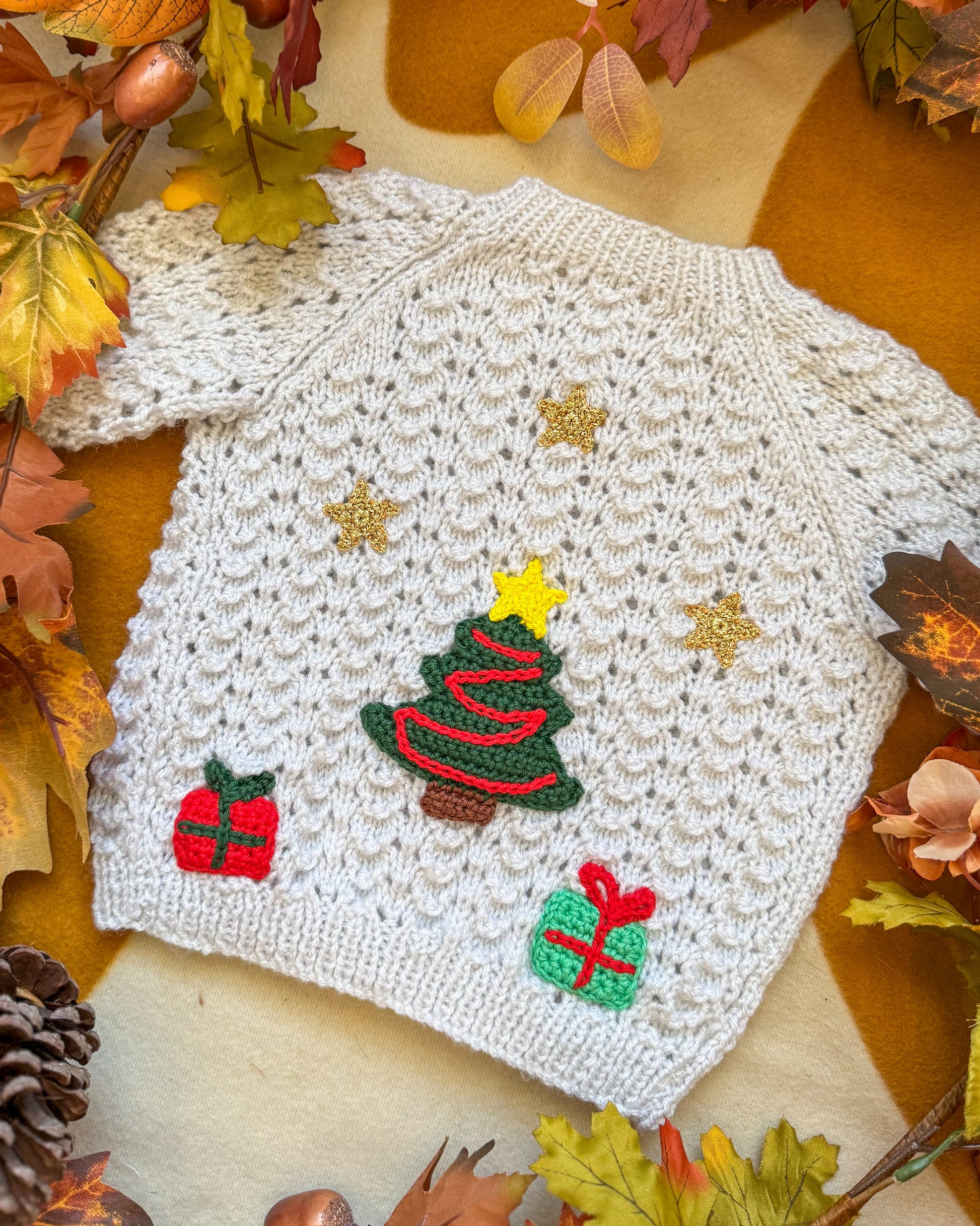 White baby cardigan with Christmas tree design and festive motifs for holiday celebrations