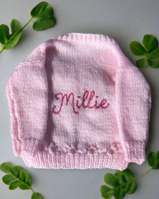 Pink hand-knitted baby cardigan with the name Millie embroidered and design a unique cardigan on our Knit Builder