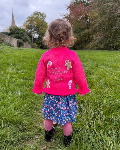 Little Flower Knits festive personalised kids cardigan in pink with gingerbread and candy cane embellishments