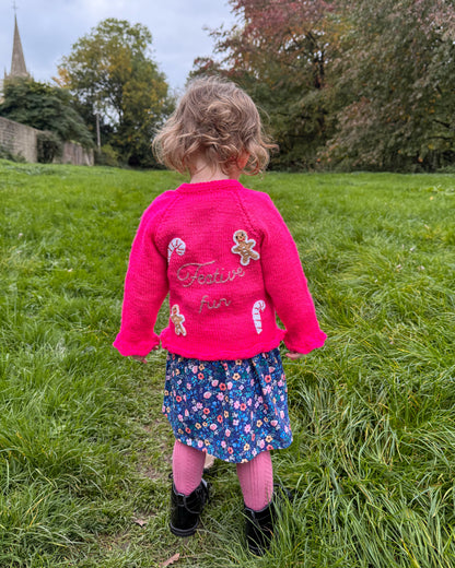 Bright pink festive personalised kids cardigan featuring candy cane and gingerbread embellishments
