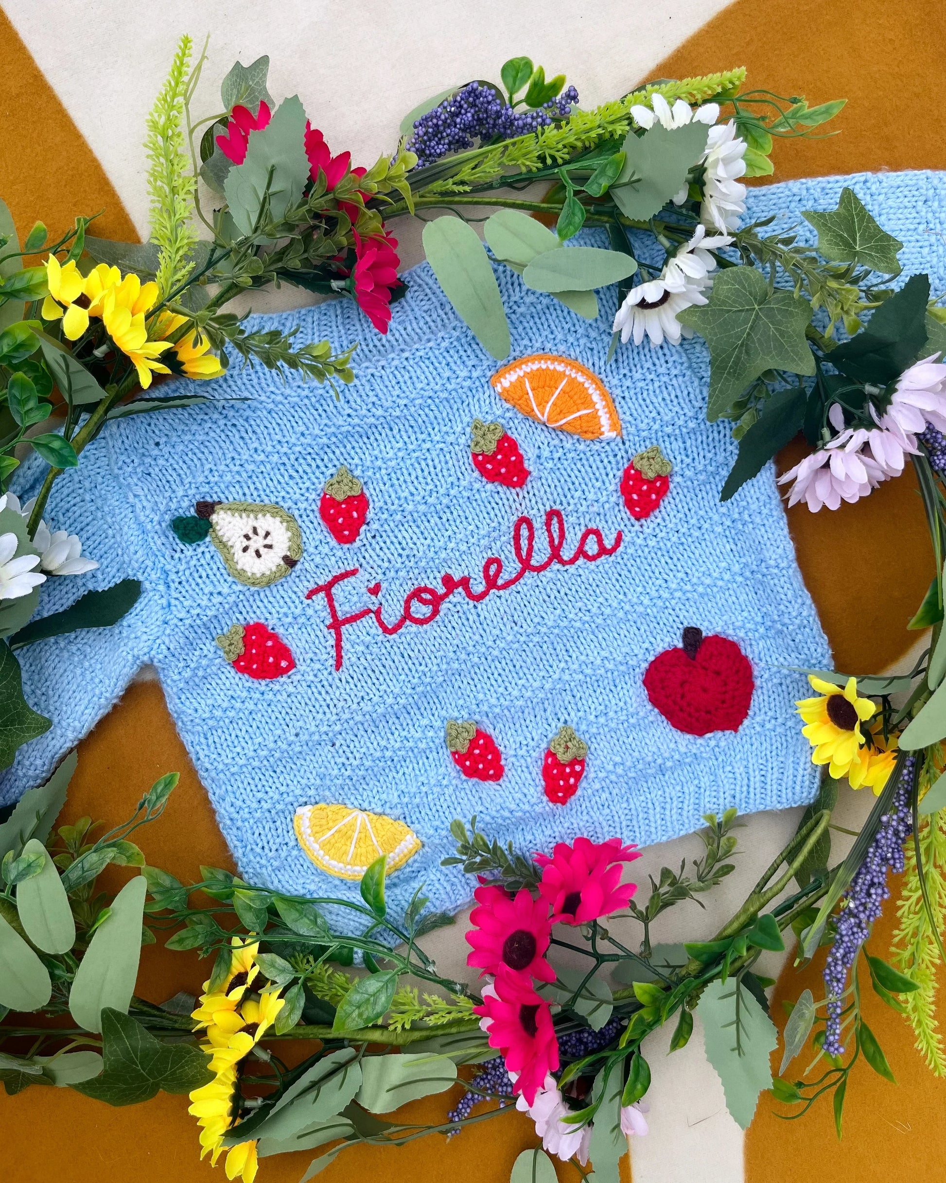 Little Flower Knits fruit pattern cardigan for toddlers in blue with embroidered fruit and name Fiorella