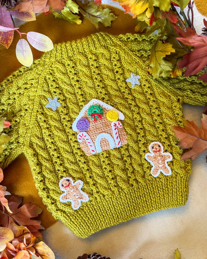 Gingerbread cottage baby cardigan in green with intricate cable knit and festive gingerbread appliques