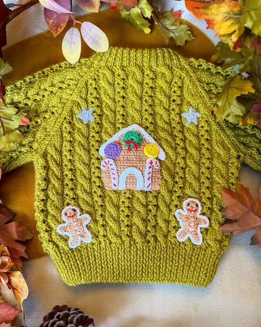 Gingerbread cottage baby cardigan in green with whimsical holiday embroidery and a textured cable knit design