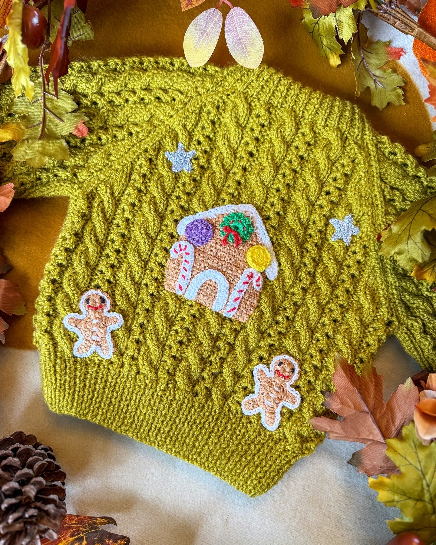 Gingerbread cottage baby cardigan in green with decorative gingerbread house and gingerbread men