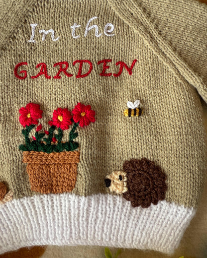 Handmade baby cardigan UK featuring floral and hedgehog designs with vibrant embroidery