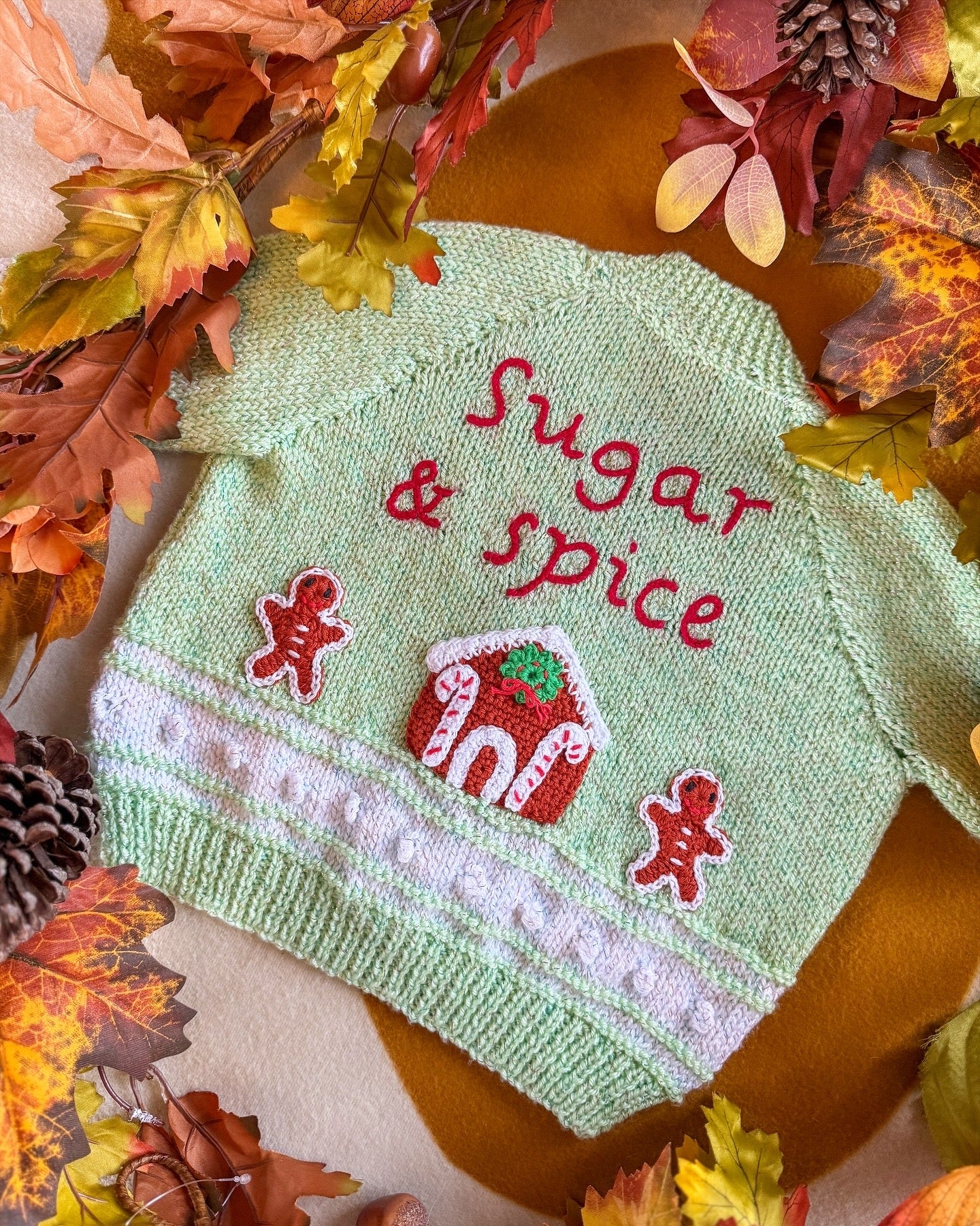 Handmade baby cardigan UK featuring 'Sugar & Spice' design with gingerbread house and gingerbread men