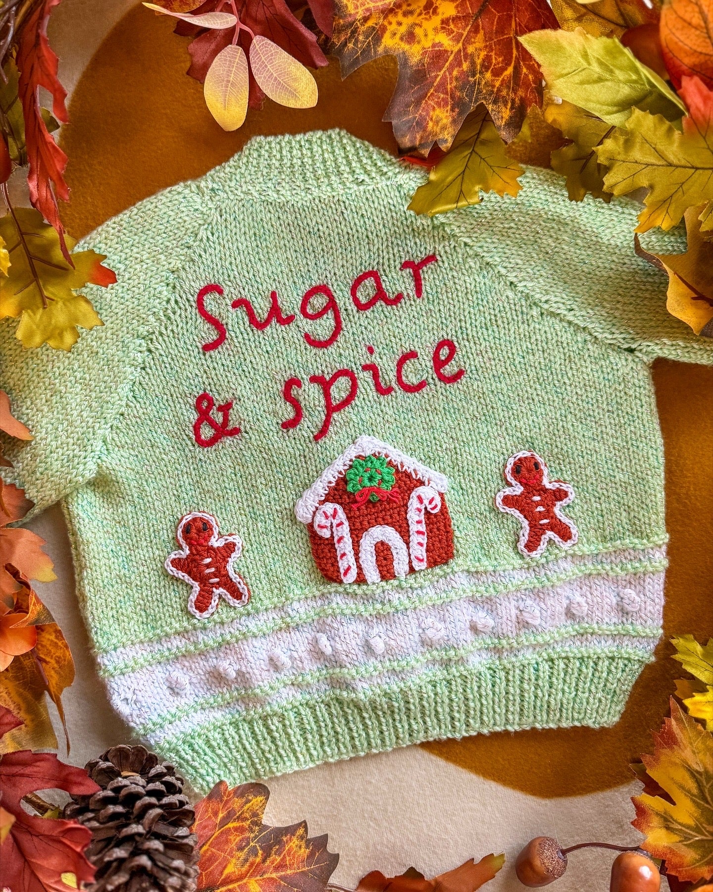 Handmade baby cardigan UK in green featuring 'Sugar & Spice' with gingerbread decorations