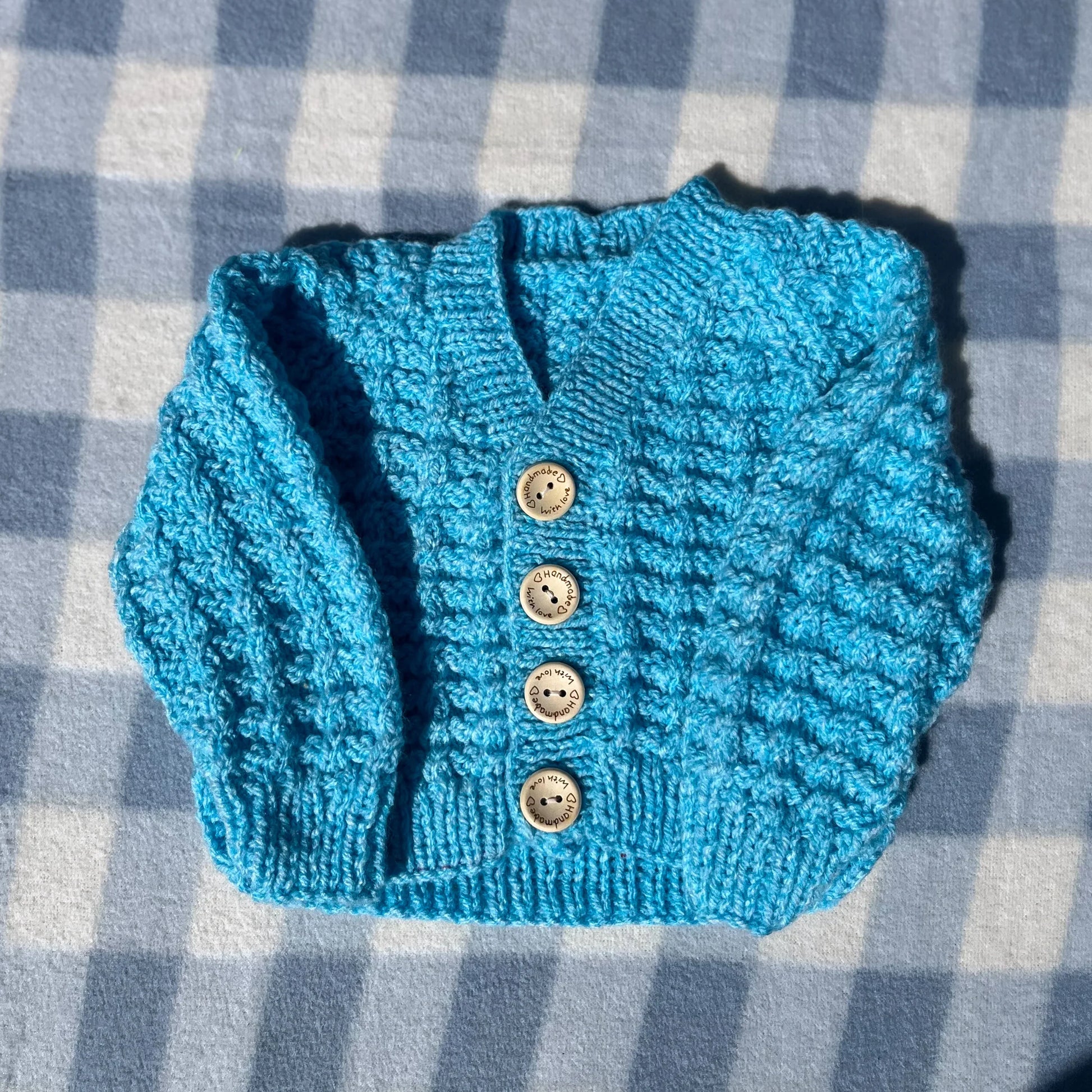 Blue newborn cardigan with rainbow textured knit and four wooden buttons by Little Flower Knits
