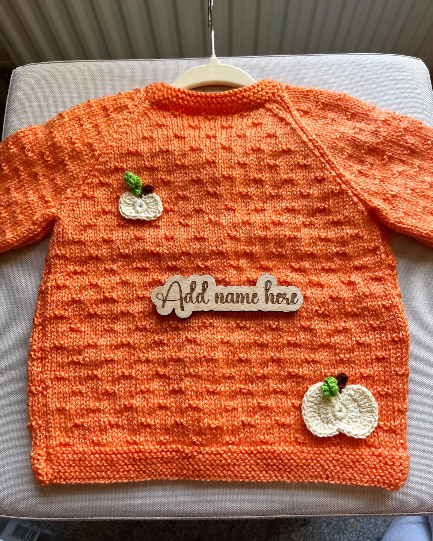 Orange hand knitted toddler cardigan with white pumpkin appliques and personalised name tag custom pumpkin outfit for toddlers