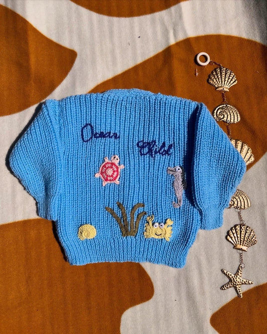 Blue knitted baby jumper with sea creatures and initials handmade ocean theme baby knitwear UK