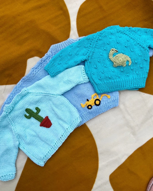 Personalised baby boy cardigan by Little Flower Knits in blue with embroidered dinosaur cactus and digger designs