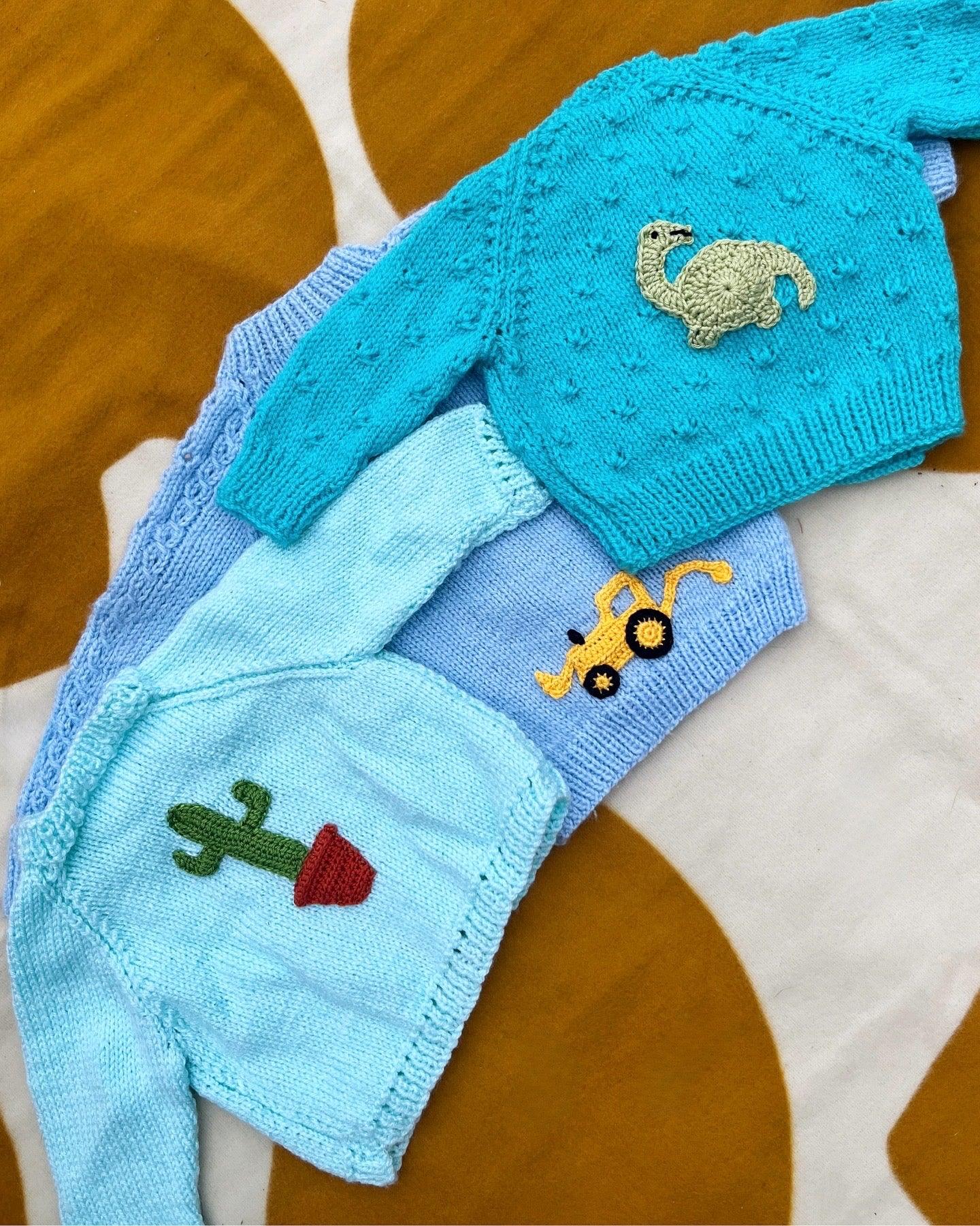 Personalised baby boy cardigan in blue with knitted dinosaur, tractor, and cactus add ons and buttons