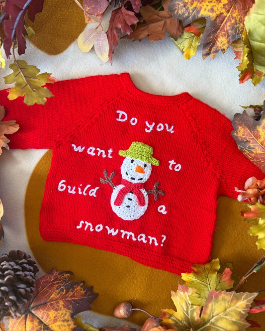 Handmade snowman baby cardigan in red with playful snowman design and text for festive occasions