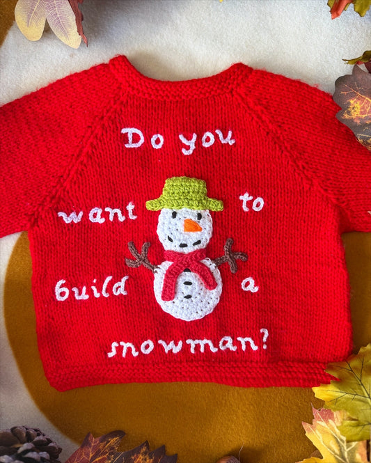 Red handmade snowman baby cardigan featuring snowman design with text for winter fun