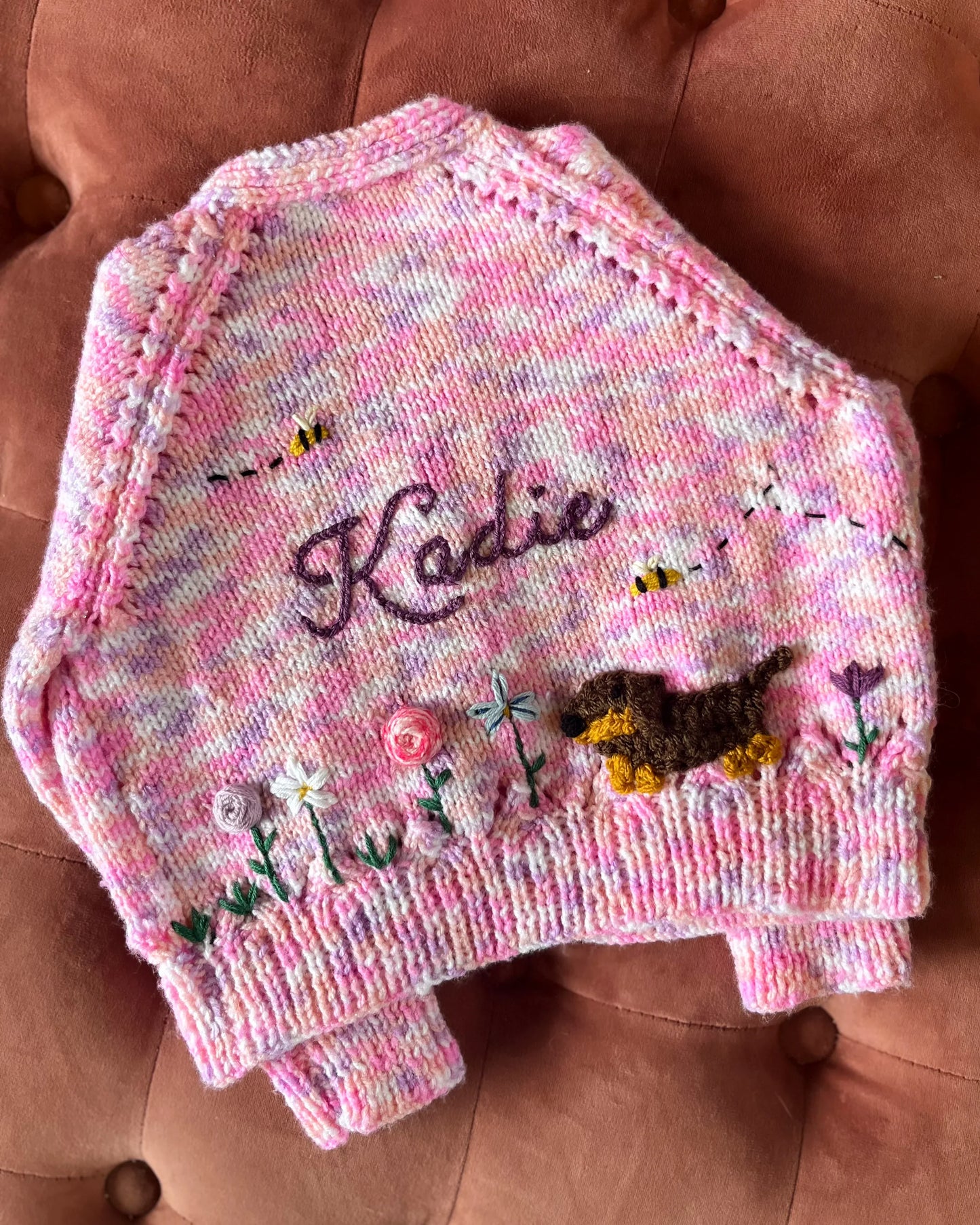 Hand-knitted personalised baby cardigan UK in pink with embroidered flowers, bees, dog and name Kadie