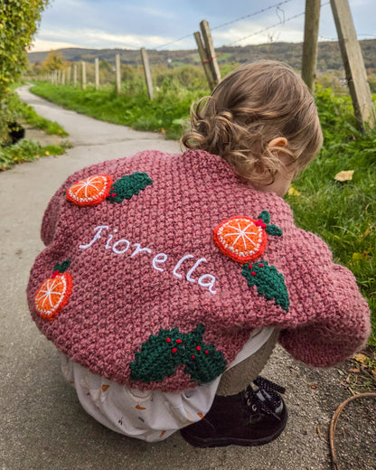 Personalised kids cardigan hand knitted with orange and green designs featuring the name Fiorella