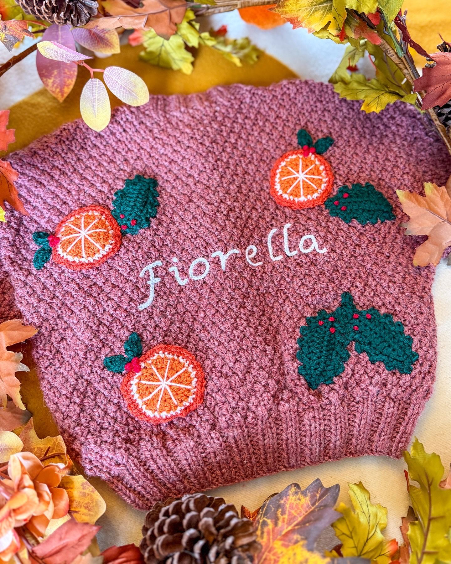 Personalised kids cardigan hand knitted with orange and holly motifs for a festive touch