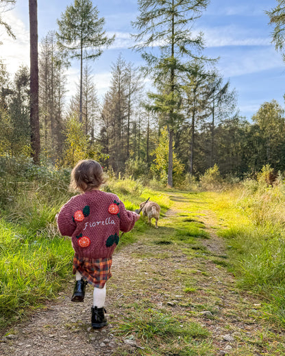 Child wearing a personalised kids cardigan hand knitted with floral designs while playing outdoors