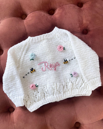 White knitted personalised rose and bee cardigan by Little Flower Knits with pink roses and embroidered bees