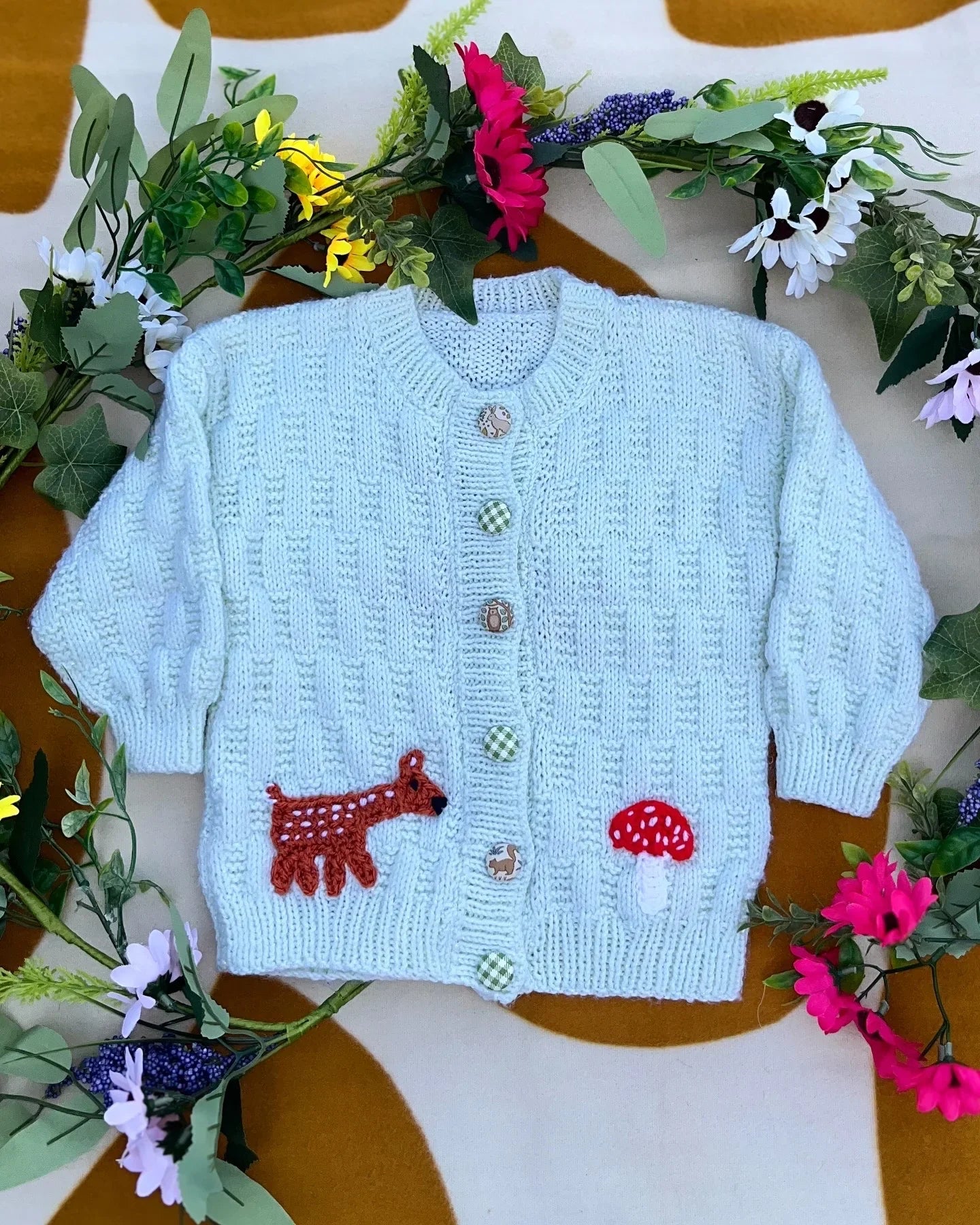 Personalised woodland cardigan for children in light blue with animal and mushroom buttons surrounded by flowers