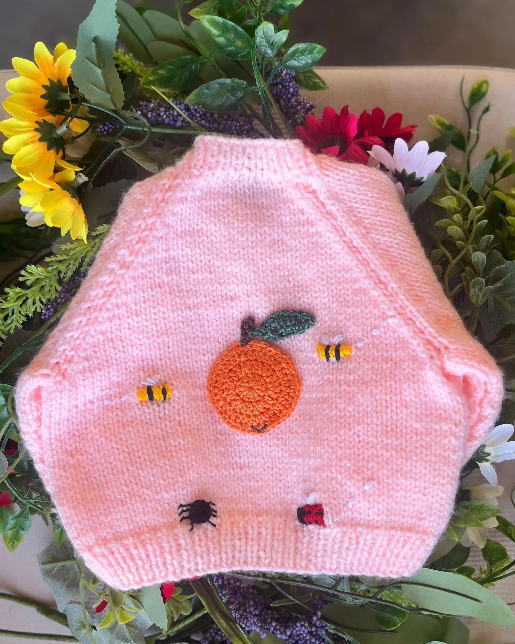 Unique baby shower gift knitted pink baby vest with embroidered orange, bees, spider, and ladybird details