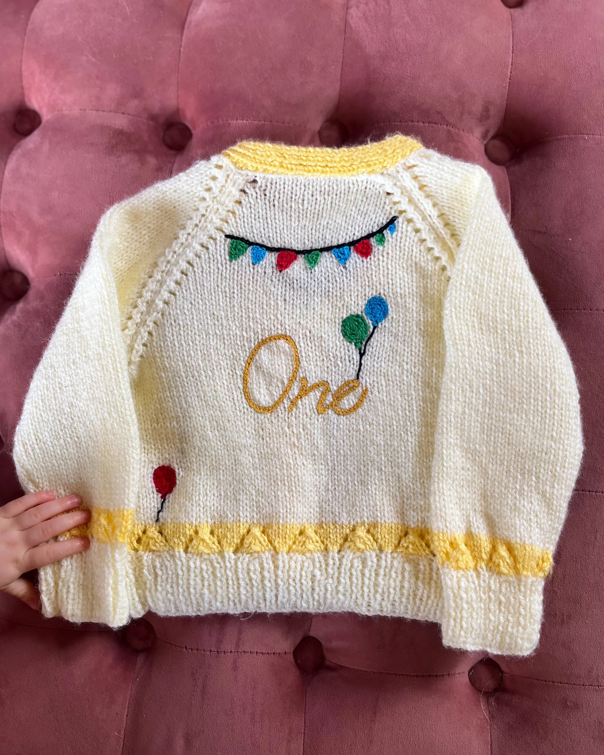 Cream knitted cardigan with yellow trim and balloon design perfect for a unique first birthday cardigan gift