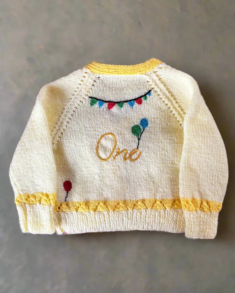 Little Flower Knits cream and yellow cardigan with balloons and banners, unique first birthday cardigan gift
