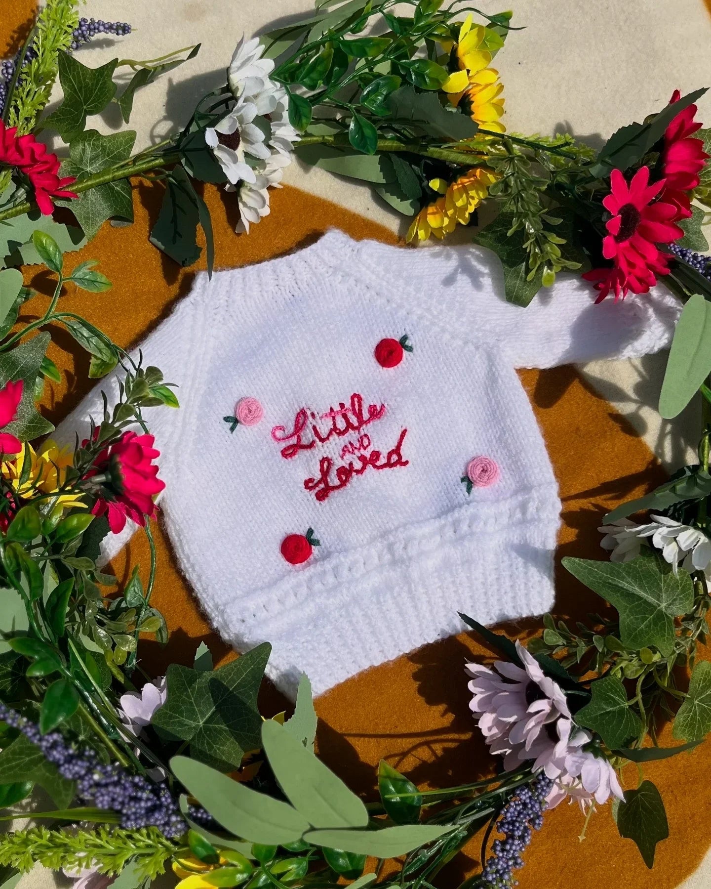 White knitted baby sweater with embroidered pink and red flowers and little and loved text unique personalised baby gift