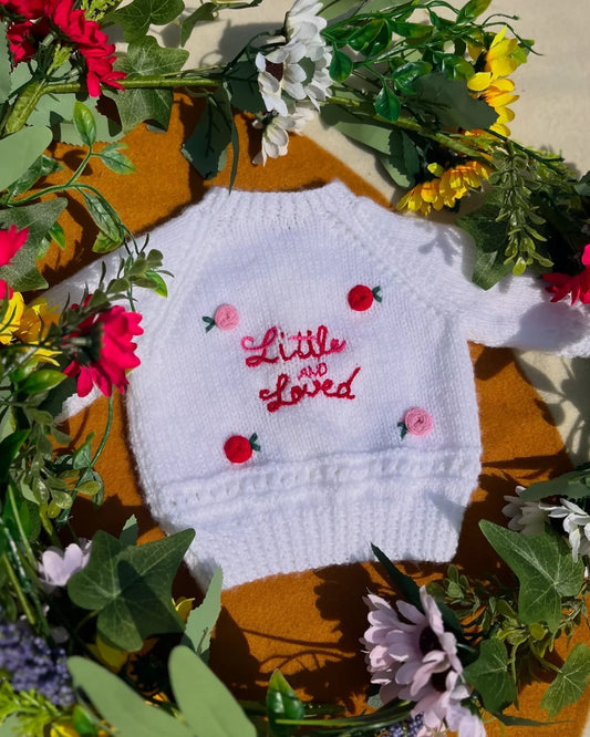 White knitted baby sweater with Little and Loved embroidery surrounded by colourful flowers unique personalised baby gift