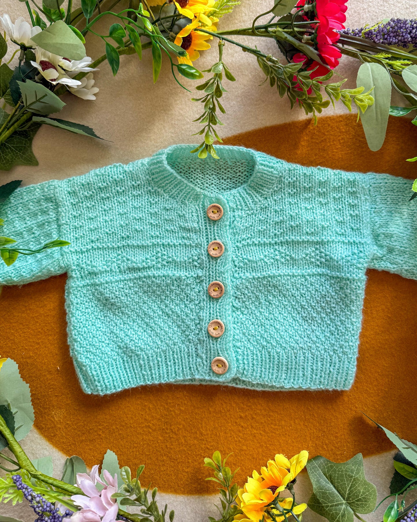 Mint green wildflower meadow baby cardigan with wooden buttons and textured pattern