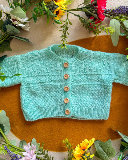 Mint green wildflower meadow baby cardigan with wooden buttons and textured pattern