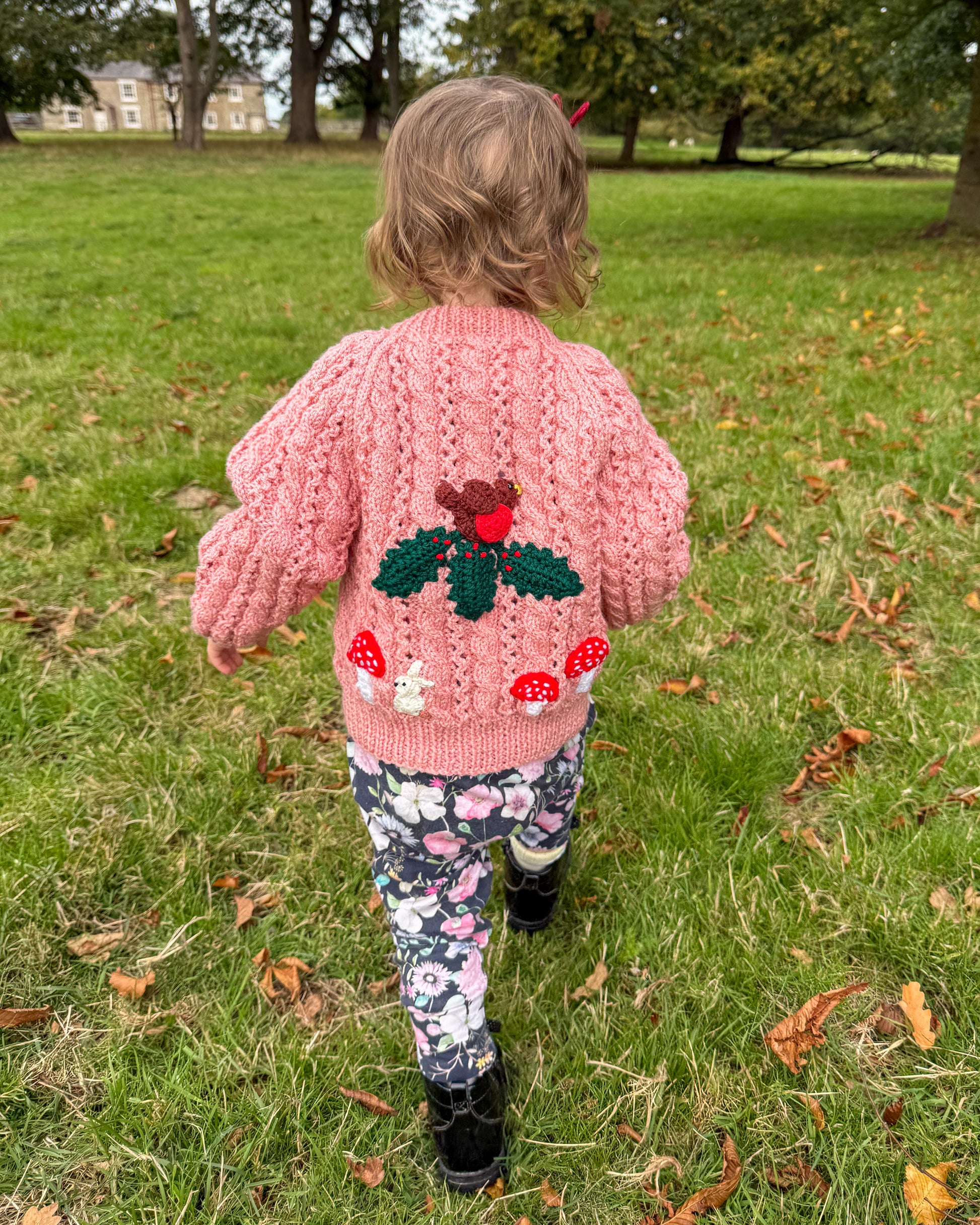 Toddler wearing a pink winter woodland cardigan for toddlers with mushroom and heart designs